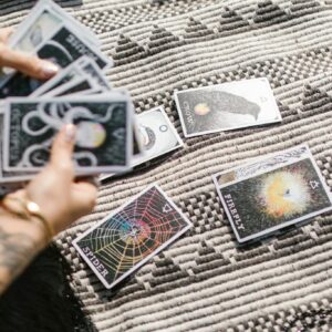 Hands dealing tarot cards for a reading on a stylish geometric rug.