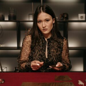 Mysterious young woman performing a fortune telling session with tarot cards.