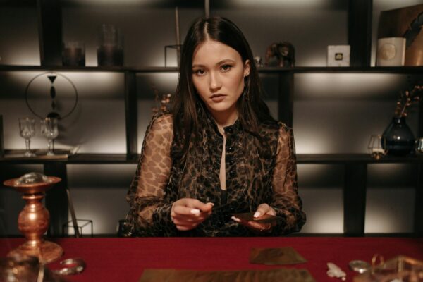 Mysterious young woman performing a fortune telling session with tarot cards.